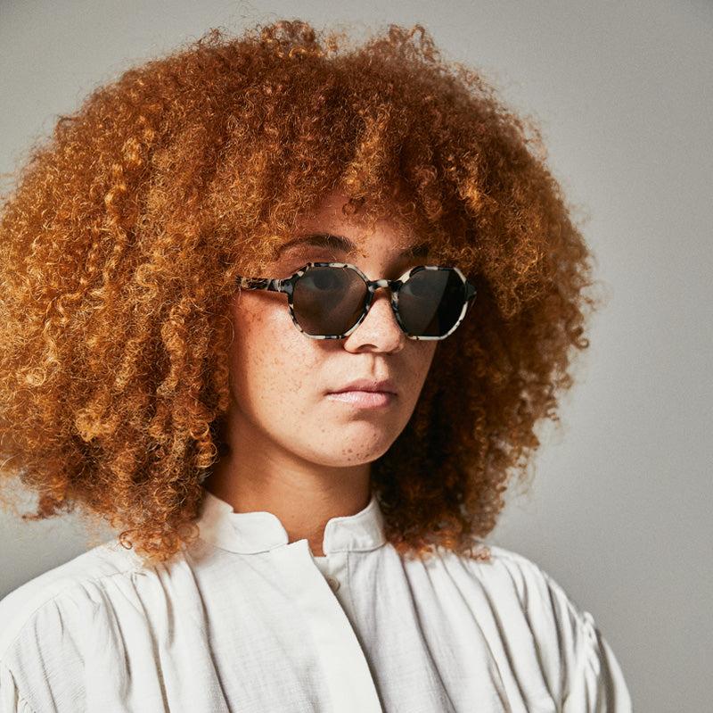 Female model wearing black and white polarised sunglasses from Ozeano