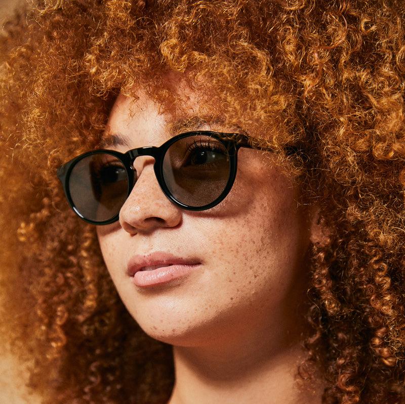 Female model wearing black Wategos polarised sunglasses