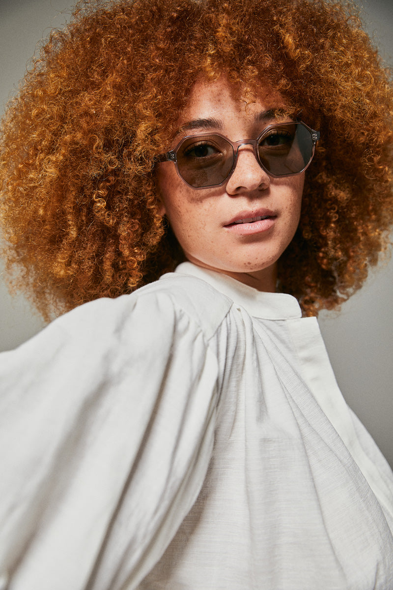 Female model wearing grey octagonal shape sunglasses 